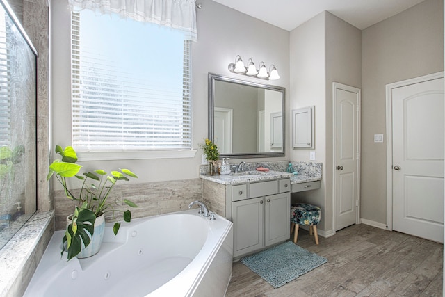 bathroom featuring a relaxing tiled tub, wood-type flooring, and vanity