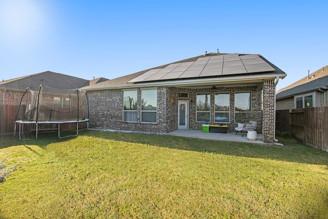 rear view of house with a trampoline, ceiling fan, a yard, and a patio area