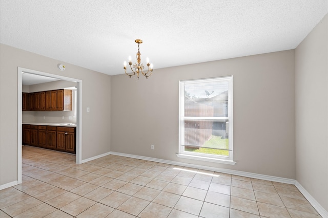 unfurnished dining area with light tile patterned floors, an inviting chandelier, and a textured ceiling