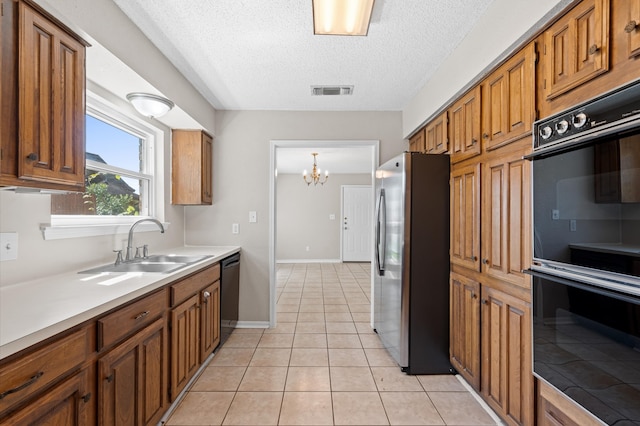 kitchen featuring black appliances, sink, a notable chandelier, light tile patterned floors, and a textured ceiling