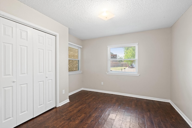 unfurnished bedroom with a textured ceiling, a closet, and dark hardwood / wood-style flooring