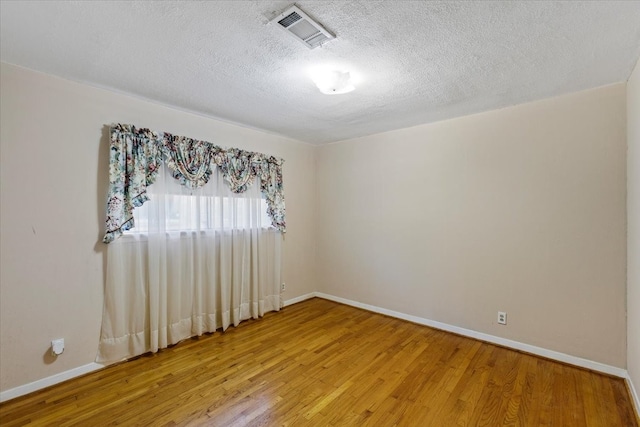 empty room with hardwood / wood-style floors and a textured ceiling