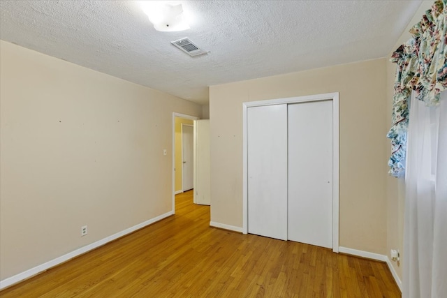 unfurnished bedroom with a closet, a textured ceiling, and light hardwood / wood-style flooring