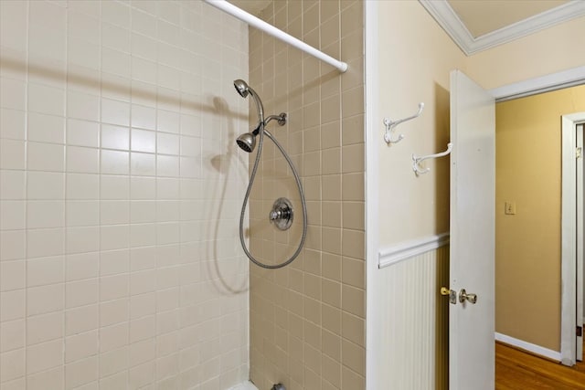 bathroom with a tile shower, wood-type flooring, and crown molding