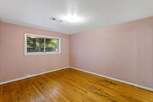 unfurnished room with hardwood / wood-style floors and a textured ceiling