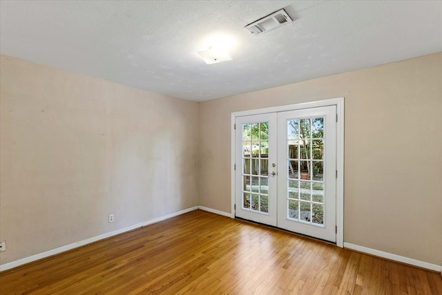 spare room featuring french doors and light hardwood / wood-style floors