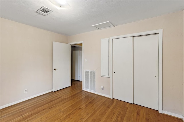 unfurnished bedroom with a closet, hardwood / wood-style floors, and a textured ceiling