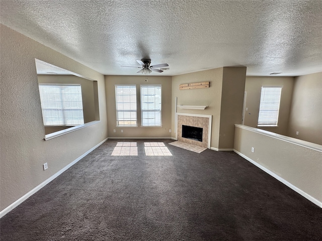 unfurnished living room with dark colored carpet, a tile fireplace, and a textured ceiling