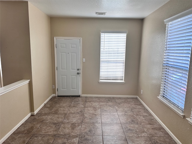 tiled foyer entrance with a textured ceiling