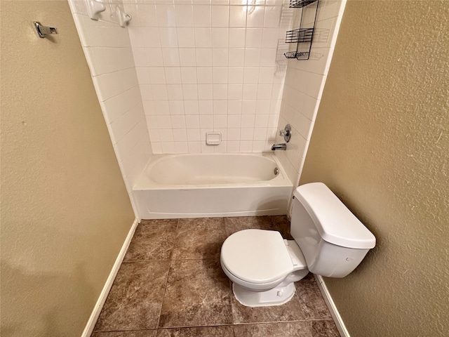 bathroom featuring tile patterned flooring, tiled shower / bath combo, and toilet