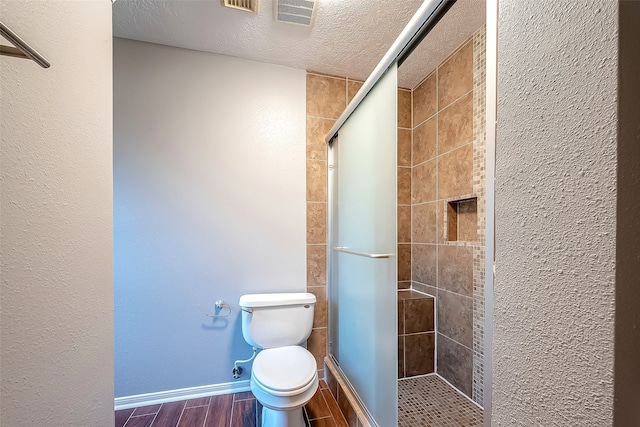 bathroom featuring toilet, an enclosed shower, and a textured ceiling