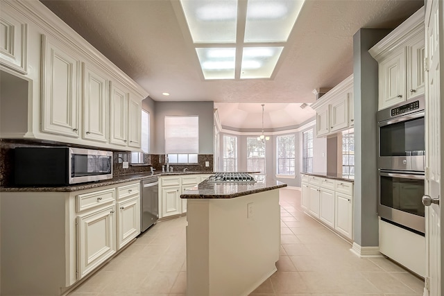 kitchen featuring kitchen peninsula, appliances with stainless steel finishes, dark stone countertops, light tile patterned floors, and a center island