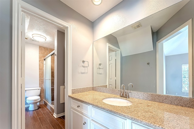 bathroom with toilet, a shower with door, hardwood / wood-style floors, a textured ceiling, and vanity