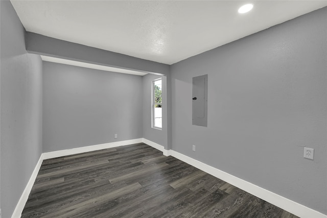 spare room with electric panel and dark wood-type flooring