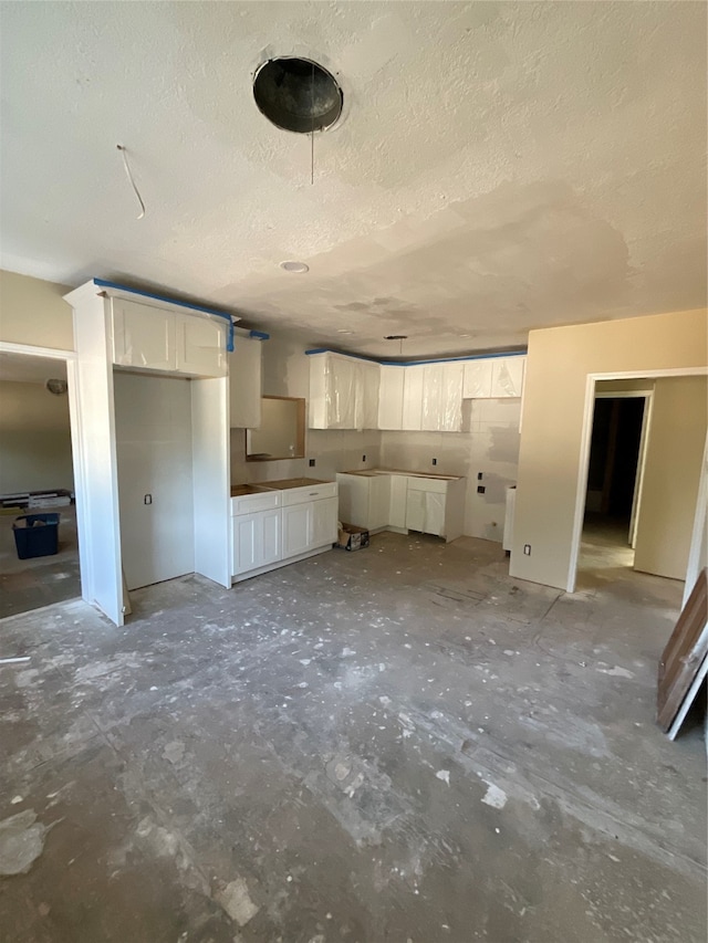 unfurnished living room with concrete flooring and a textured ceiling