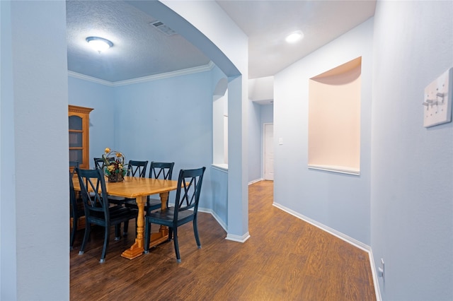 dining area with a textured ceiling, dark hardwood / wood-style flooring, and crown molding