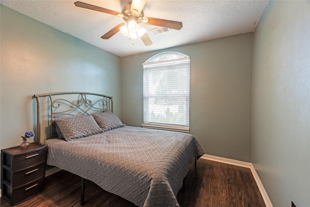 bedroom with a textured ceiling, ceiling fan, and dark wood-type flooring