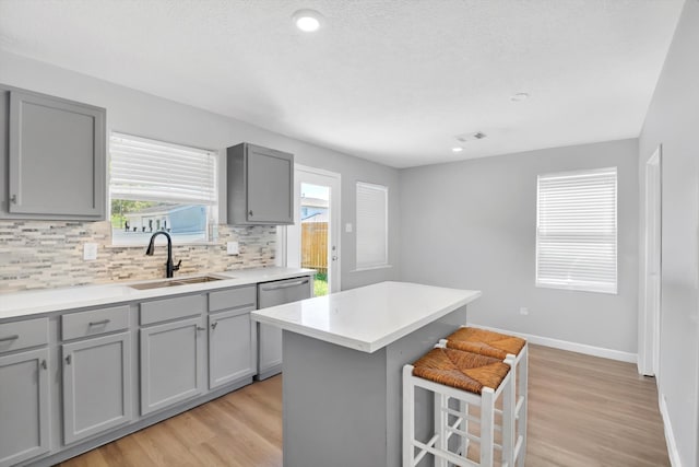 kitchen featuring gray cabinets, a breakfast bar area, sink, and a center island