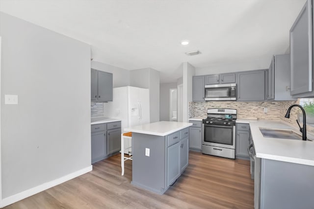 kitchen featuring gray cabinets, appliances with stainless steel finishes, sink, and a center island