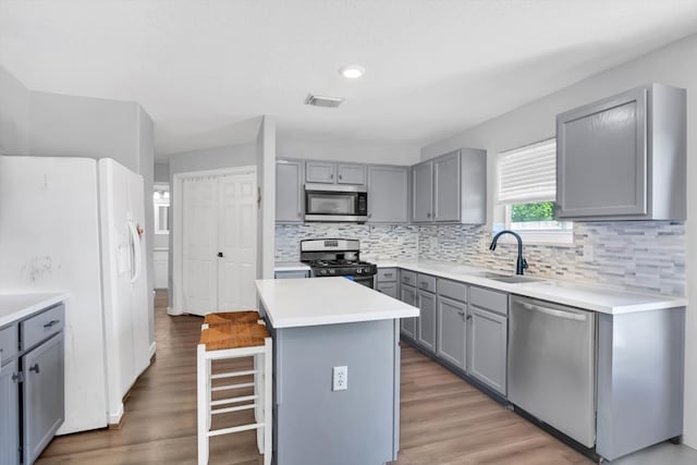 kitchen featuring stainless steel appliances, wood-type flooring, sink, and a center island