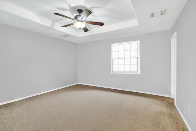 carpeted spare room featuring ceiling fan and a tray ceiling