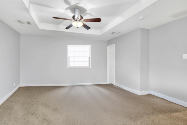 carpeted spare room featuring ceiling fan and a raised ceiling