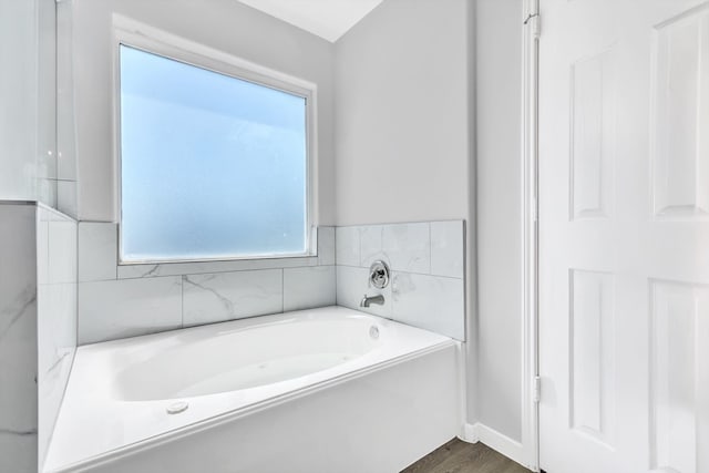 bathroom with wood-type flooring, a washtub, and a wealth of natural light