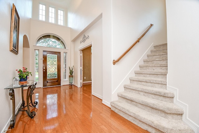 foyer featuring light wood-type flooring and a towering ceiling