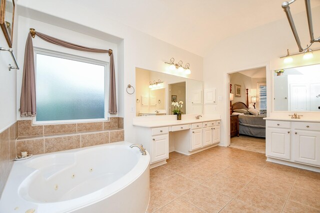 bathroom with tile patterned flooring, a bathtub, lofted ceiling, and vanity