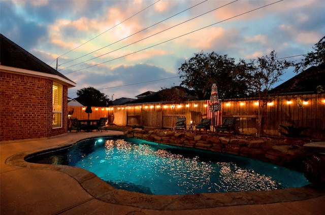 pool at dusk with a patio area