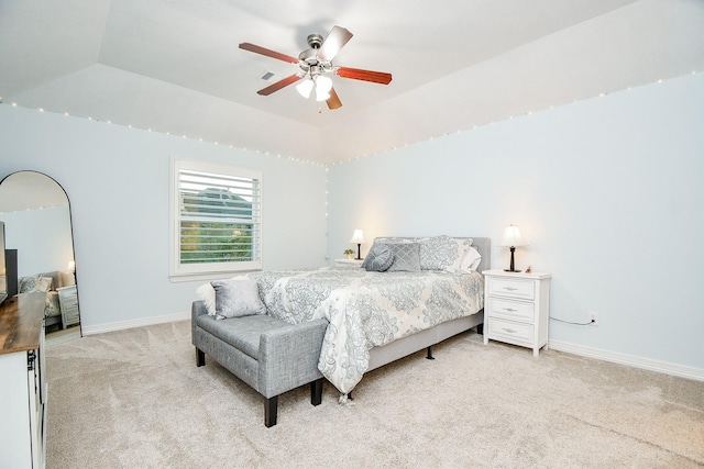 bedroom with light carpet, a tray ceiling, baseboards, visible vents, and a ceiling fan