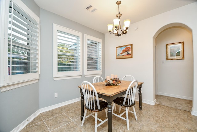 dining area with baseboards, arched walkways, a notable chandelier, and visible vents