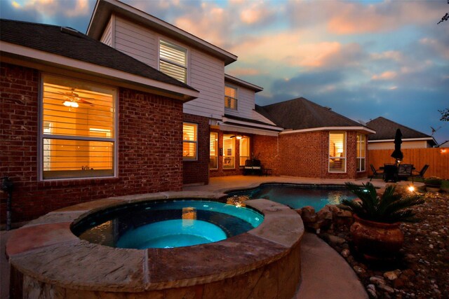 pool at dusk with an in ground hot tub and a patio