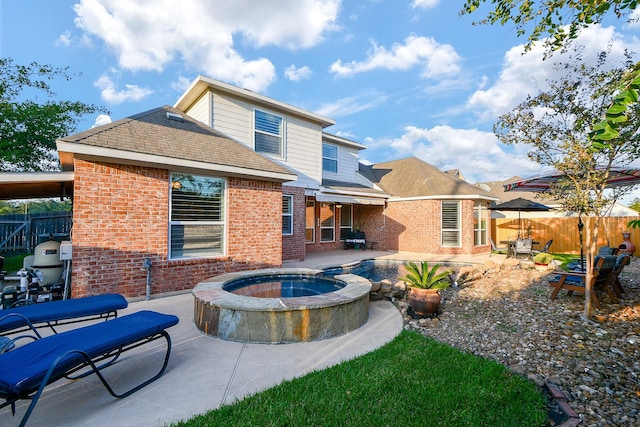 back of property featuring an in ground hot tub and a patio area