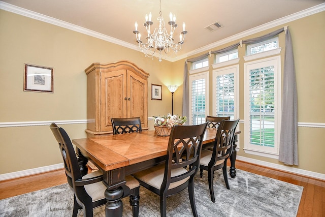 dining space featuring wood-type flooring, a notable chandelier, and ornamental molding