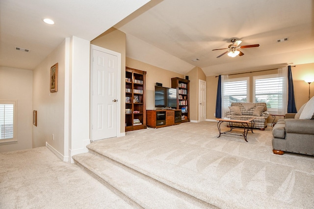 carpeted living room with ceiling fan, plenty of natural light, and vaulted ceiling