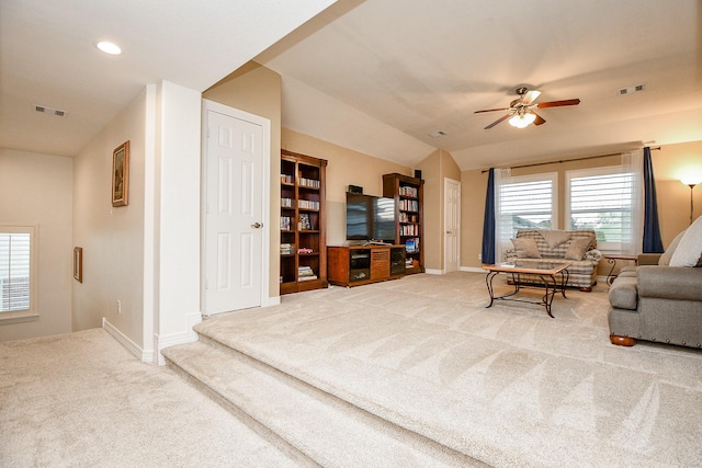 carpeted living room with vaulted ceiling, visible vents, baseboards, and a ceiling fan