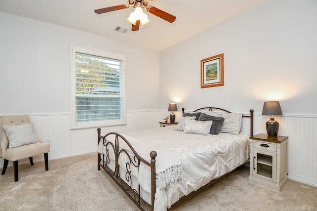 bedroom featuring visible vents, ceiling fan, wainscoting, and light carpet