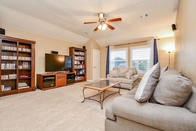 living area with visible vents, light colored carpet, vaulted ceiling, and ceiling fan