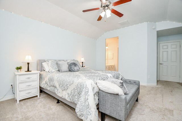 bedroom featuring ceiling fan, ensuite bathroom, light carpet, and vaulted ceiling