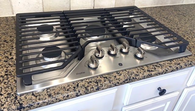 room details featuring stainless steel gas stovetop, white cabinetry, and dark countertops