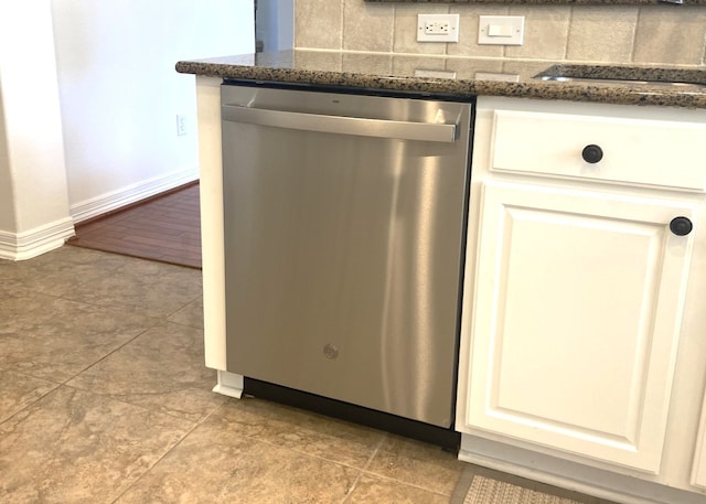 kitchen featuring backsplash, stainless steel dishwasher, dark stone counters, sink, and white cabinets