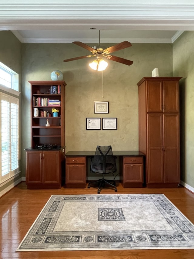 home office with crown molding, baseboards, a ceiling fan, and light wood-type flooring