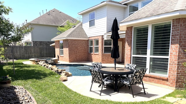 back of property featuring a jacuzzi, brick siding, fence, and a patio area