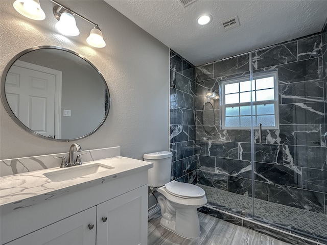 bathroom with vanity, walk in shower, hardwood / wood-style flooring, toilet, and a textured ceiling