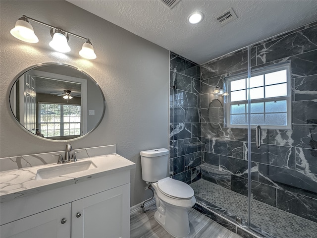 bathroom featuring a healthy amount of sunlight, ceiling fan, vanity, and toilet