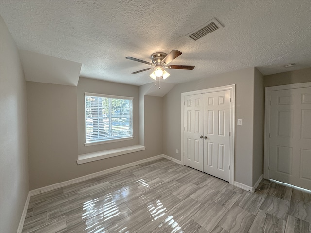 unfurnished bedroom featuring a closet, light hardwood / wood-style floors, a textured ceiling, and ceiling fan