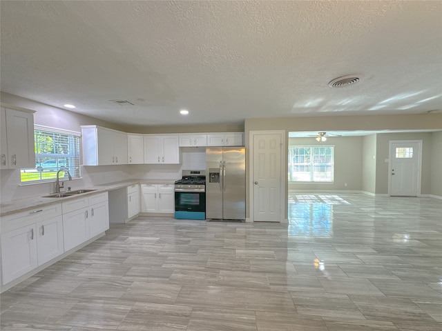 kitchen with appliances with stainless steel finishes, a healthy amount of sunlight, and white cabinets