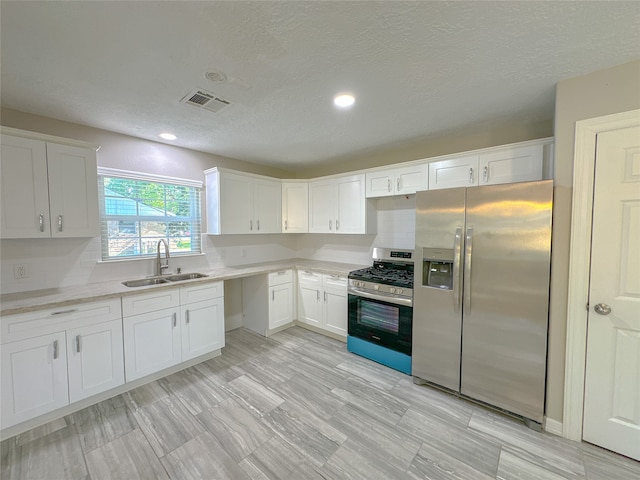 kitchen featuring a textured ceiling, stainless steel appliances, sink, and white cabinetry