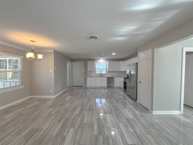 unfurnished living room with an inviting chandelier, a textured ceiling, light hardwood / wood-style flooring, and sink